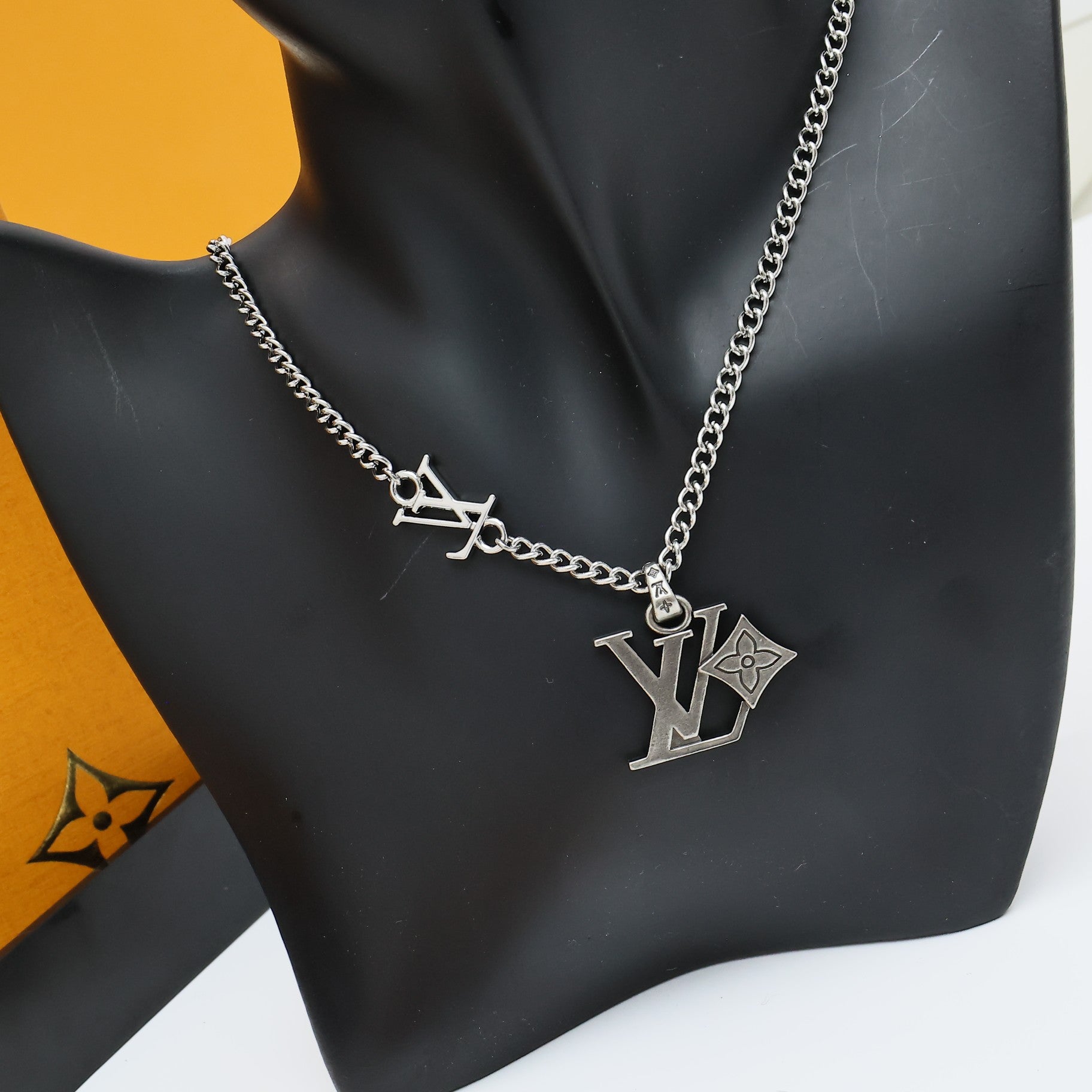 Silver LV pendant charm necklace with chain on black bust display
