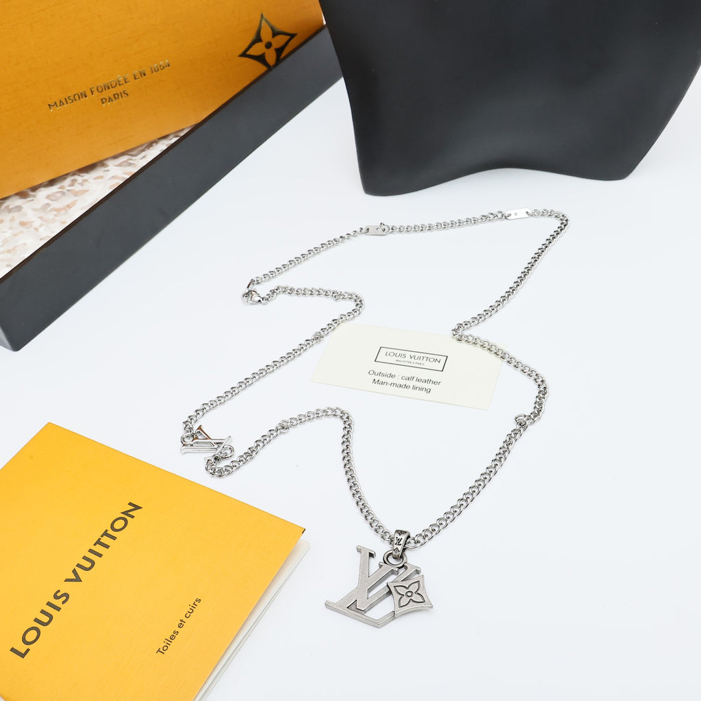 Silver LV pendant necklace with chain laid out on display stand