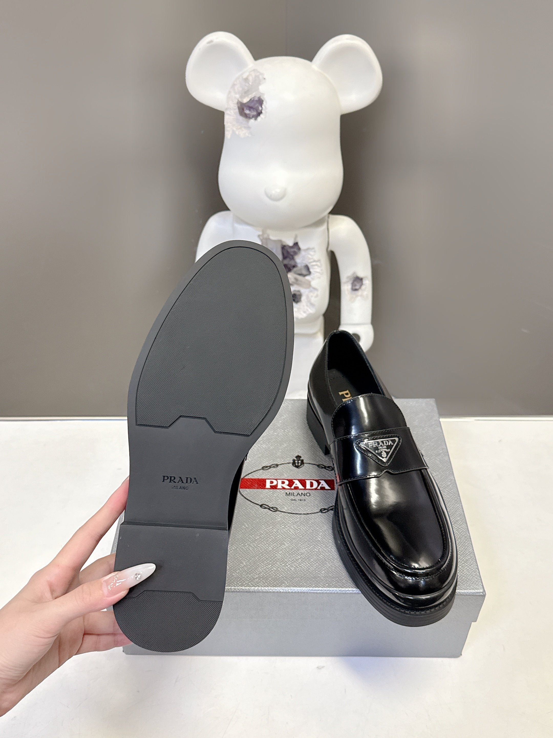 Prada unisex black loafer outsole view with ridged traction sole pattern