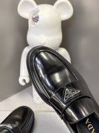 Prada unisex black leather loafer, close-up side view with logo buckle detail