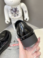 Prada unisex black leather loafer heel side view with ridged platform sole