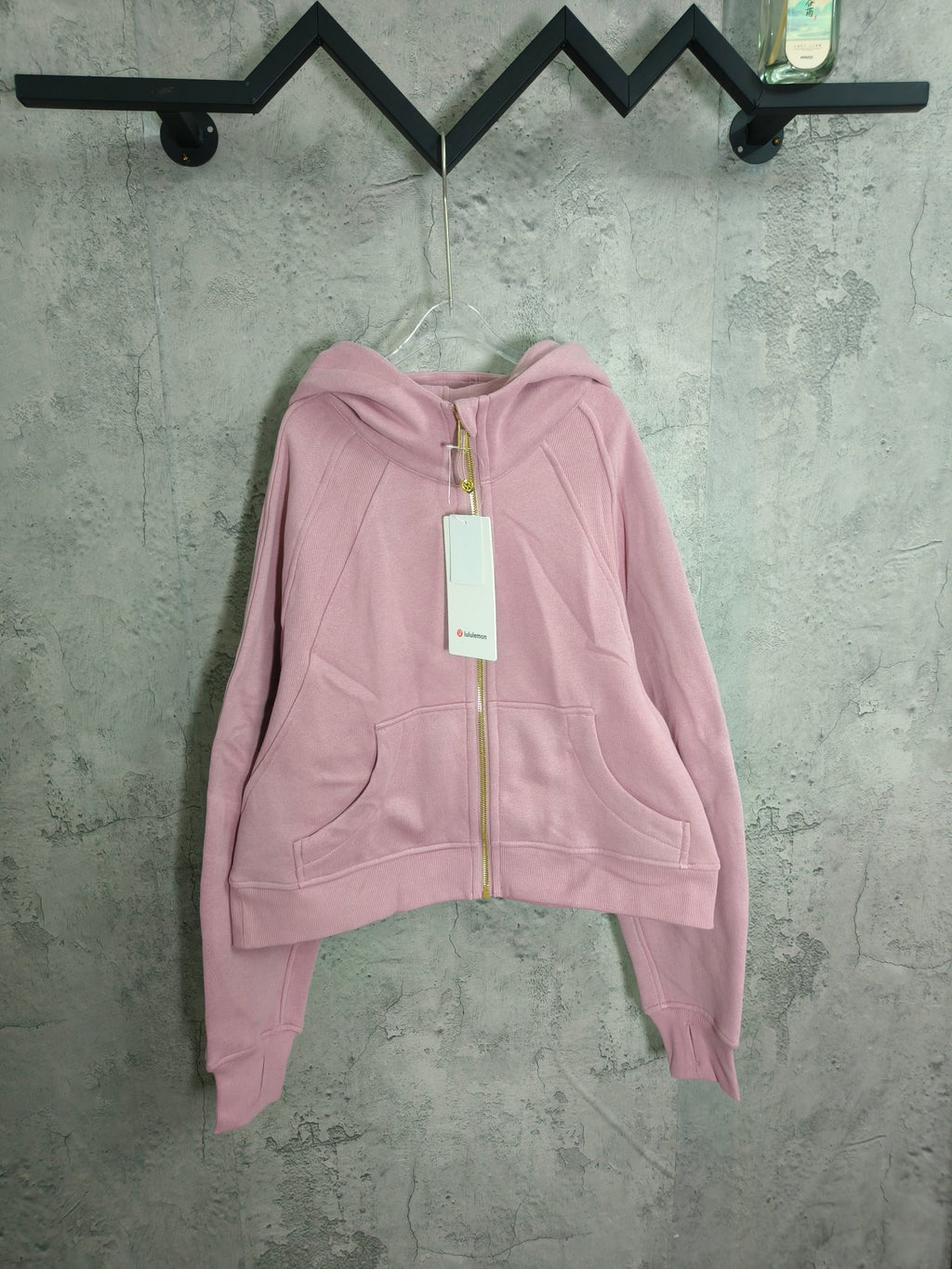 Light pink zip-up hoodie with hood, front pockets, and full-length zipper