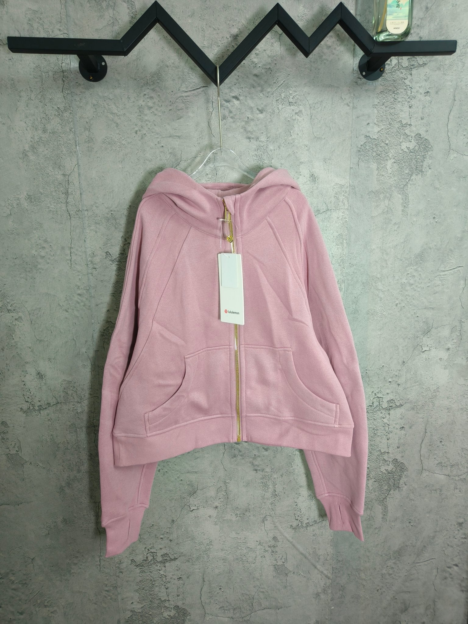 Light pink zip-up hoodie with hood, front pockets, and full-length zipper