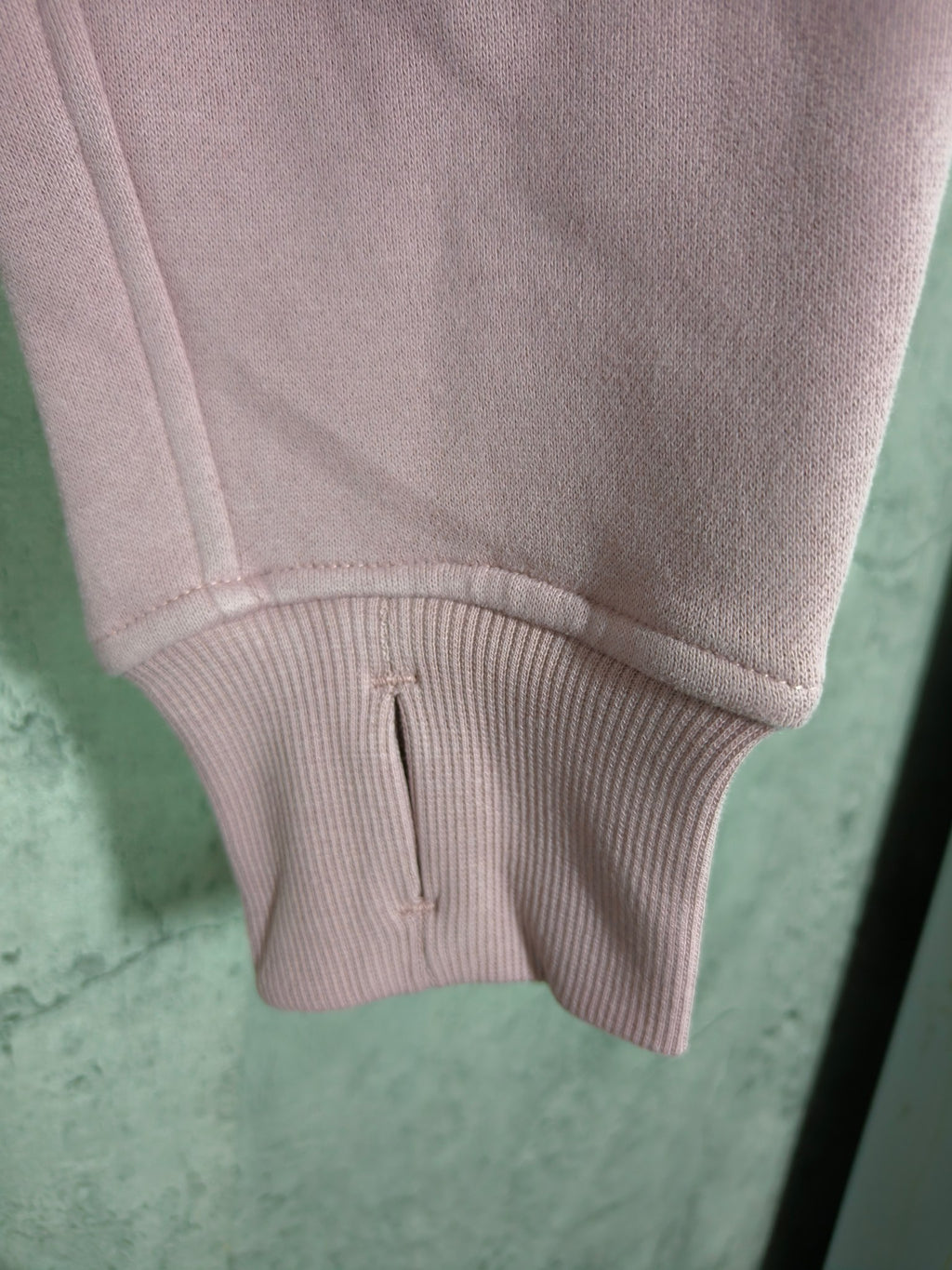 Light pink hoodie with ribbed hem and front pocket opening detail