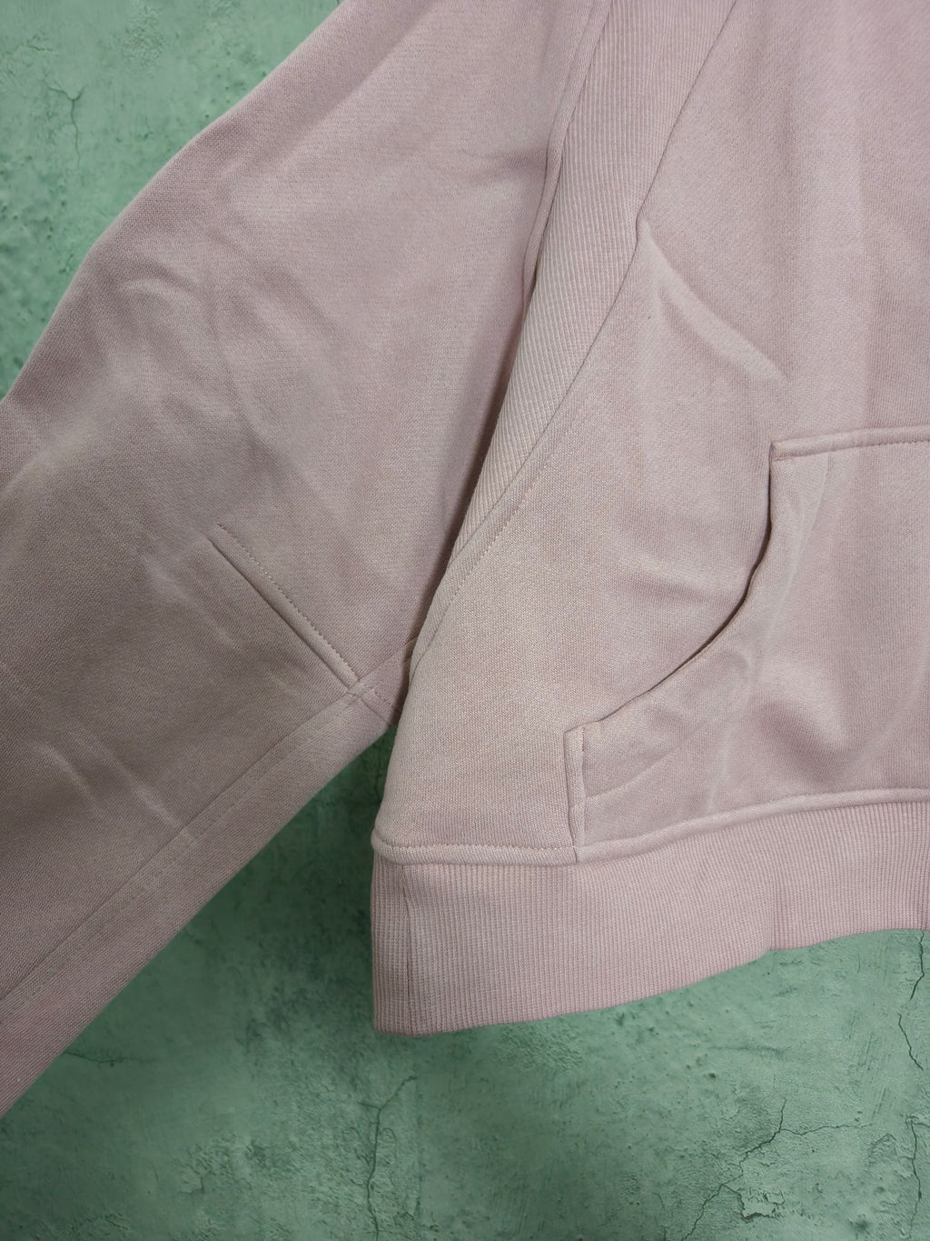 Light pink zip-up hoodie side view with ribbed cuffs and kangaroo pocket