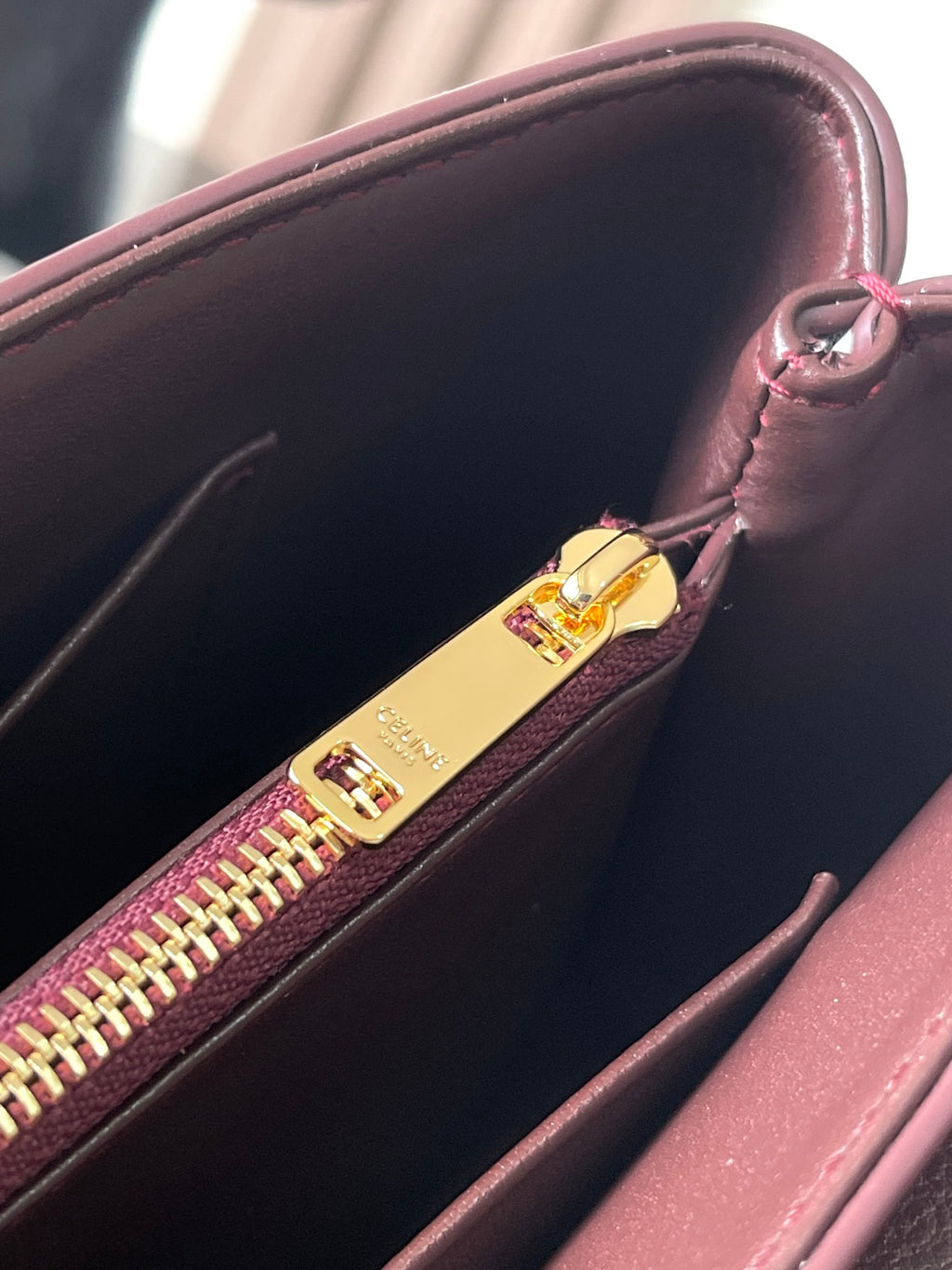 Burgundy bag interior with gold zip slider and multicolor zipper teeth.