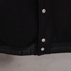 Black varsity jacket hem with ribbed cuffs and three button placket