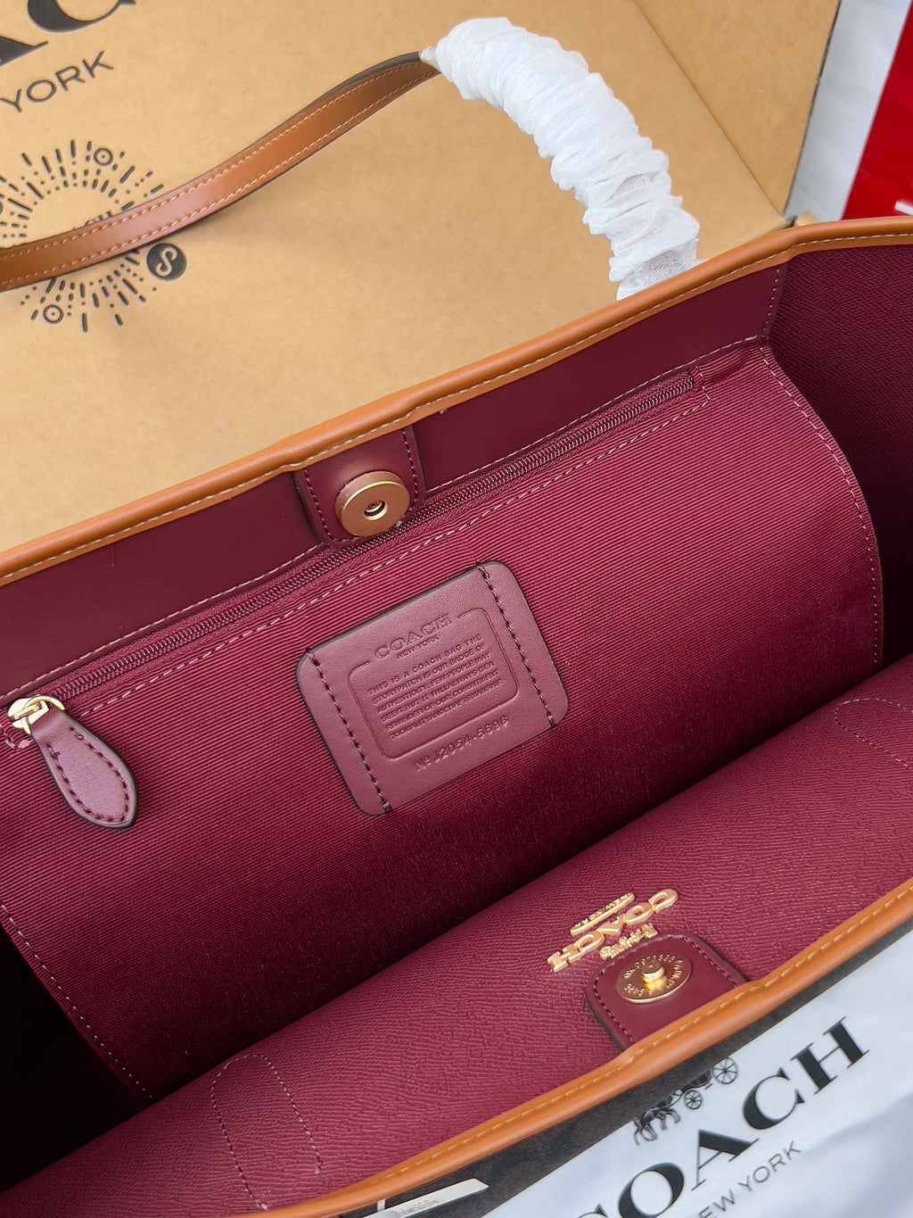 COACH burgundy tote interior with leather trim, snap pocket, and embossed logo patch
