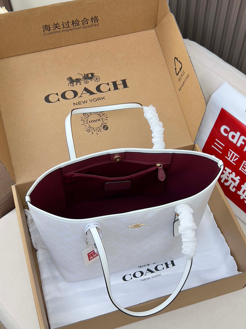 Coah tote bag opened showing burgundy lining and hanging handle charm