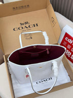 Coah tote bag opened showing burgundy lining and hanging handle charm