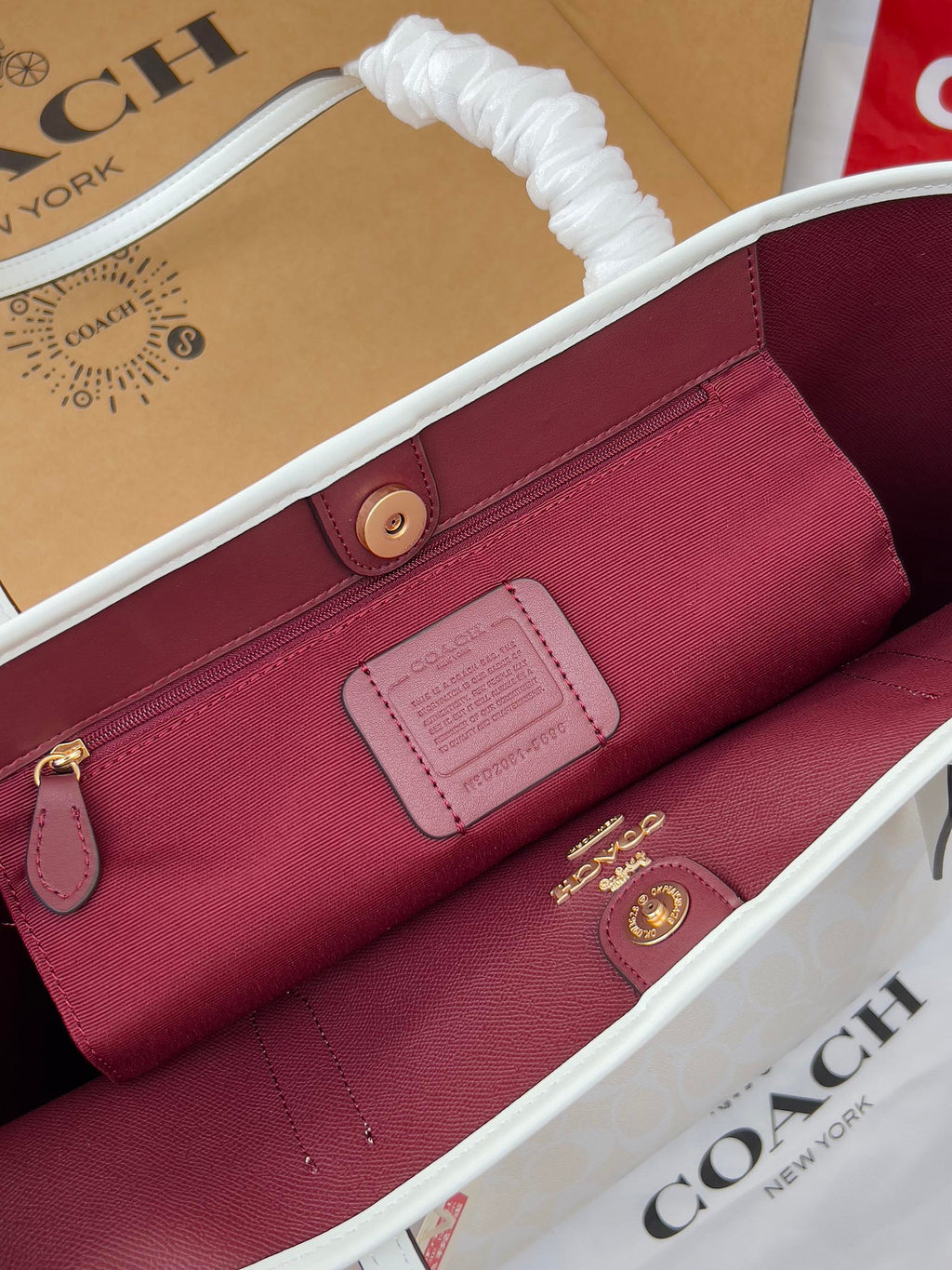 Coah burgundy zip pouch inside the tote, with logo patch and gold hardware