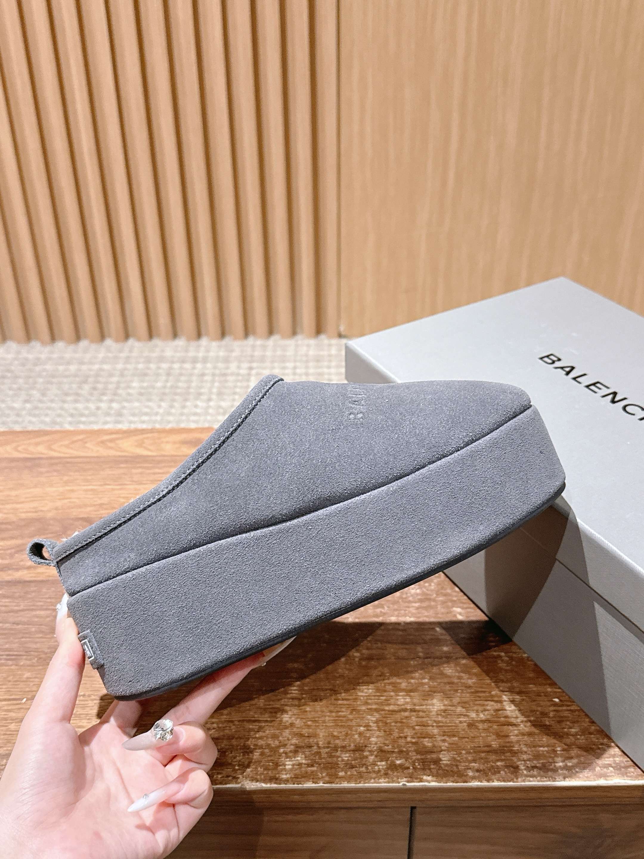 Grey Balenciaga slide sandal held in hand, wide upper strap and padded sole