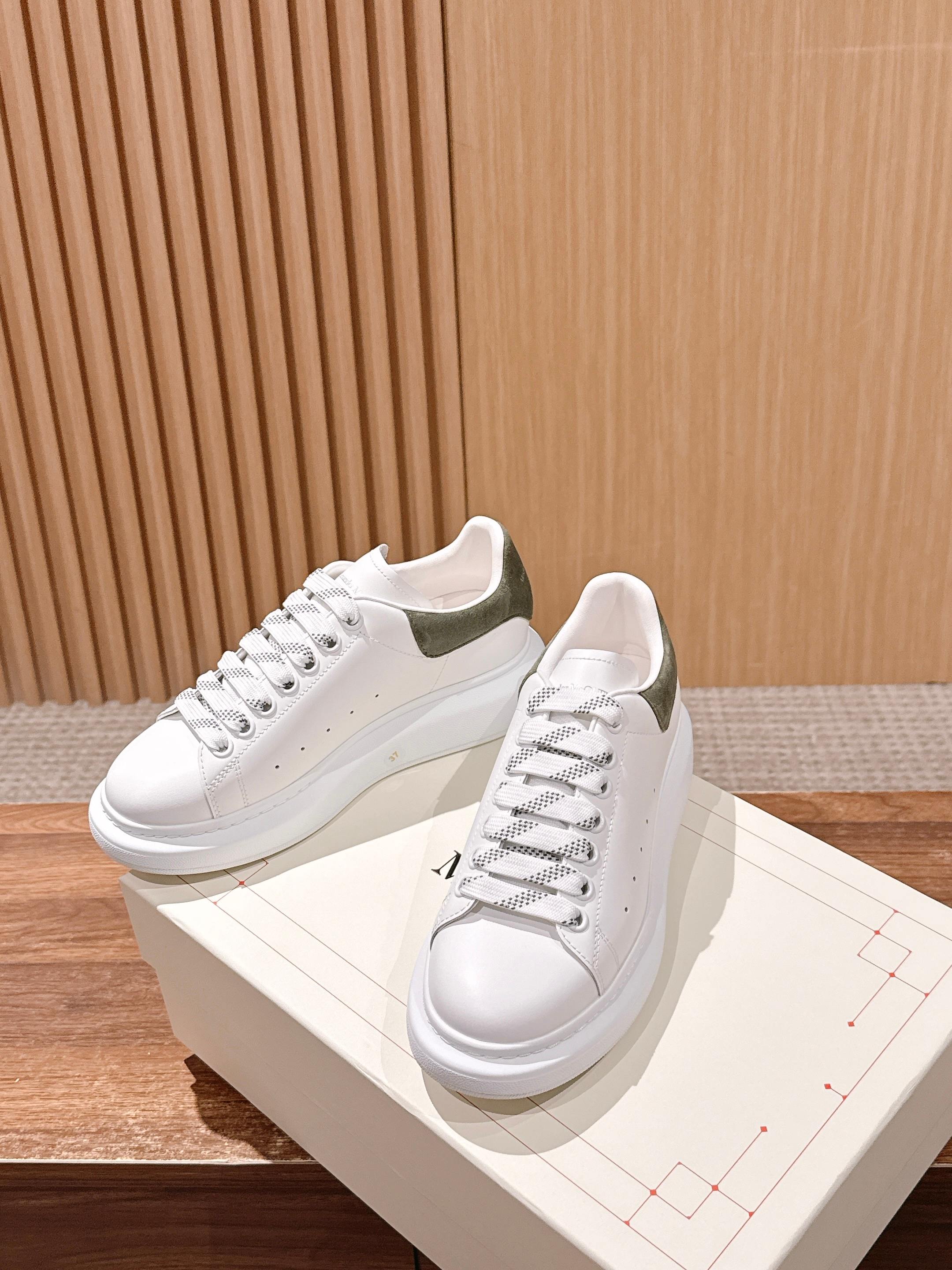 Alexander McQueen white sneakers with olive heel accents, lace-up, on shoe box