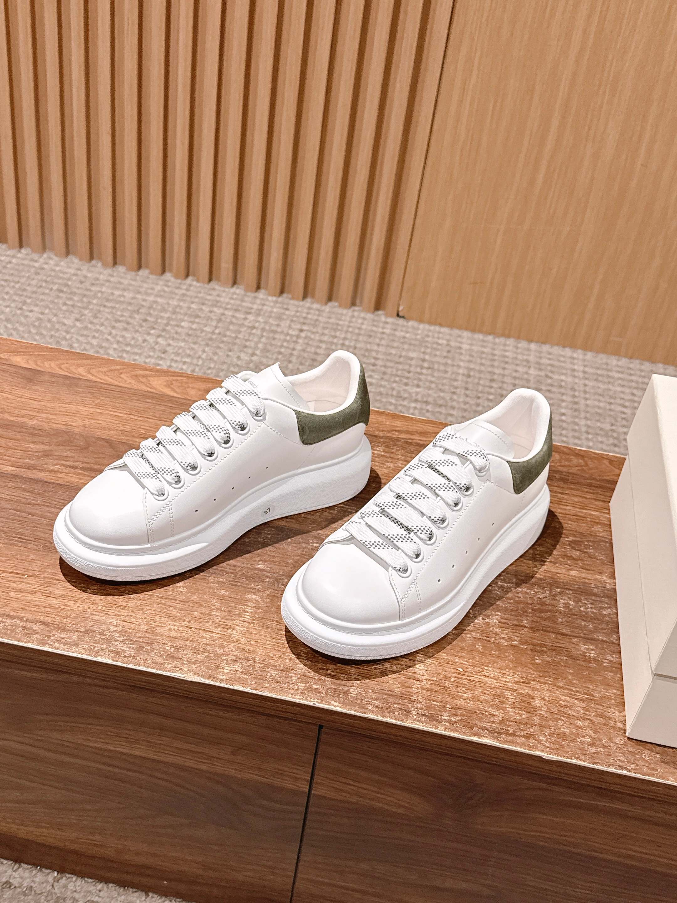 White leather sneakers with olive heel panels and lace-up front detail