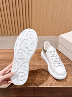 Shoe sole and side view: white lace-up sneakers with olive heel accent
