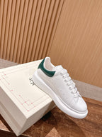 White leather sneaker with green collar lining and lace-up eyelets