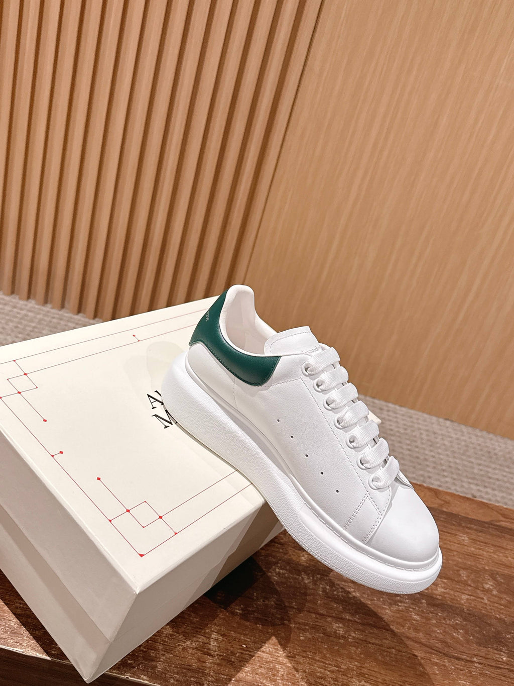 White leather sneaker with green collar lining and stitched lace eyelets