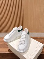 White leather sneakers with green collar lining and lace-up front