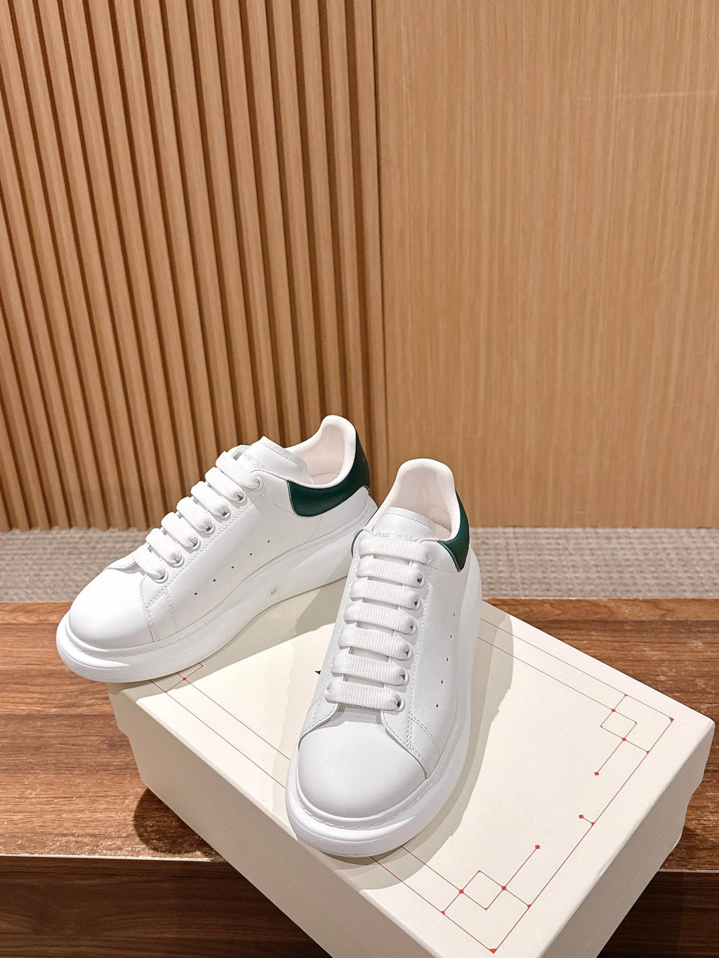 White leather sneakers with green collar lining and lace-up front