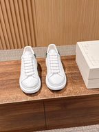 White leather sneakers with green accents, lace-up front and flat rubber sole