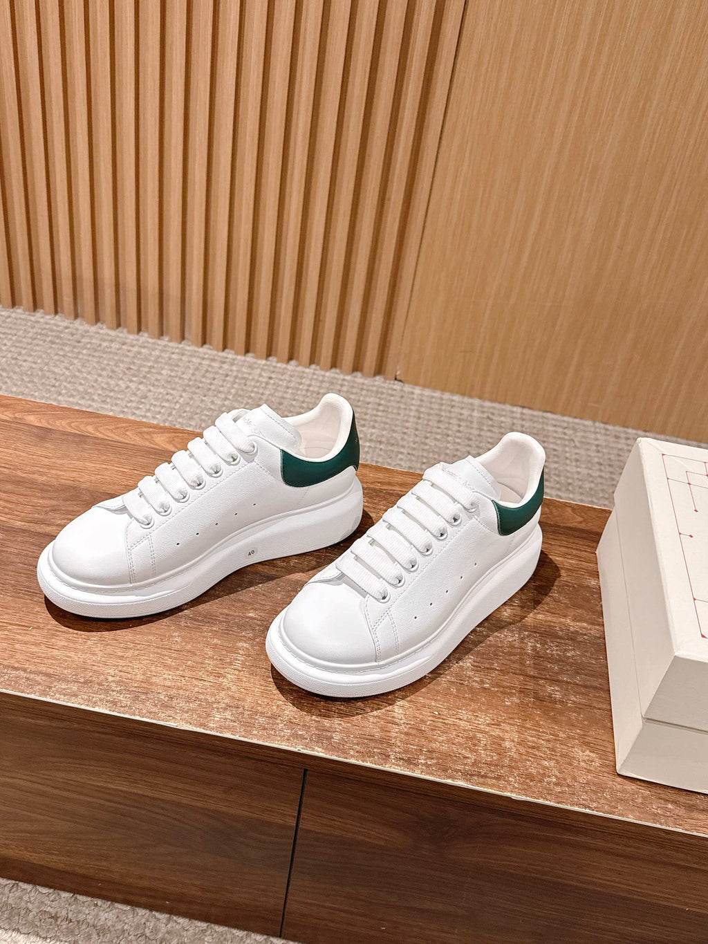 White lace-up leather sneakers with green collar lining and thick white sole