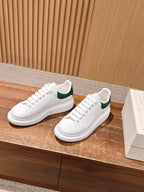 White leather sneakers with green collar lining and lace-up design