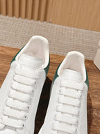White leather sneakers with green collar lining and padded tongue