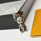 Silver bear figurine charm on a chain, shown on a dark display box