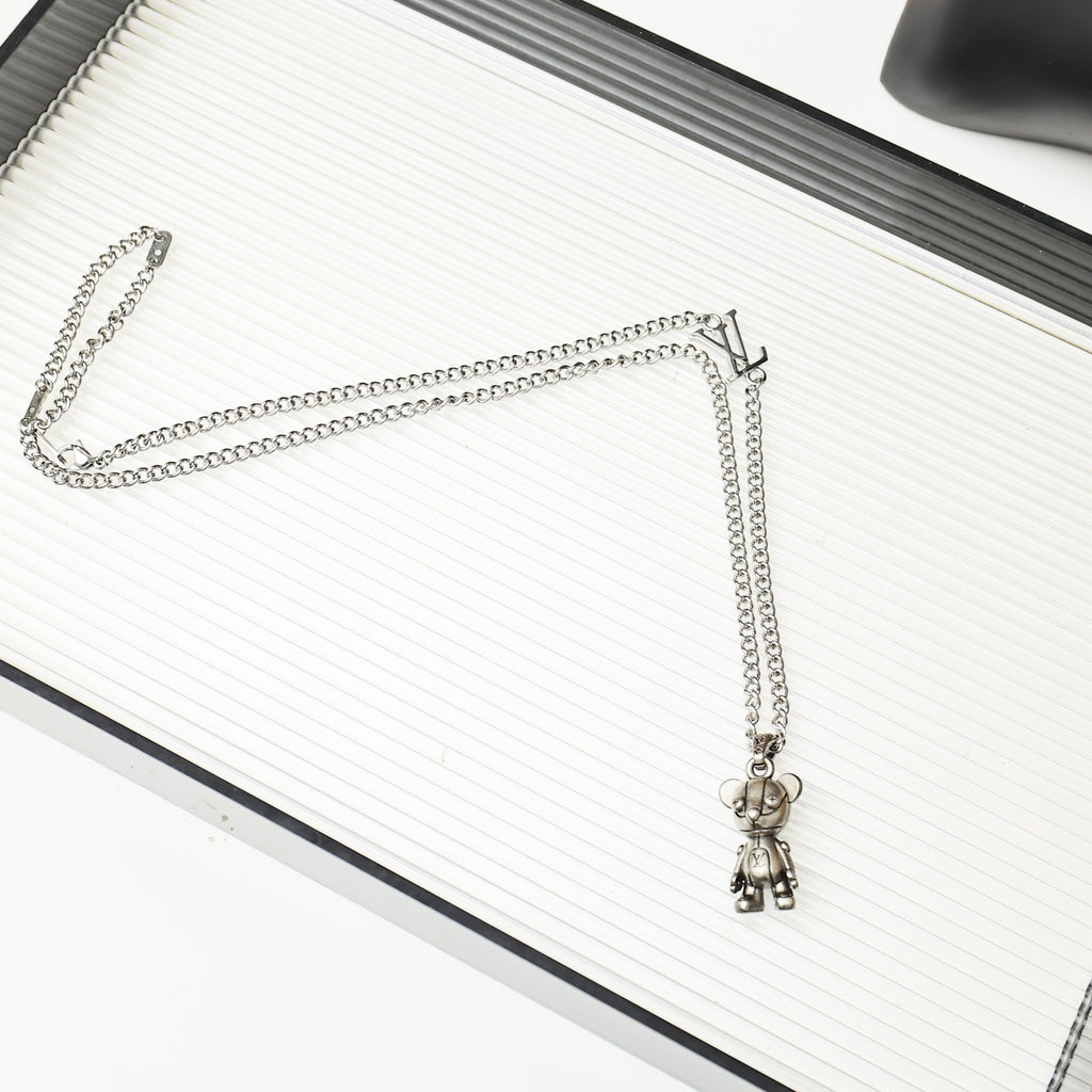 Silver chain necklace with a hanging bear charm on a white ridged book