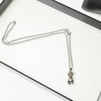 Silver chain necklace with a hanging bear charm on a white ridged book
