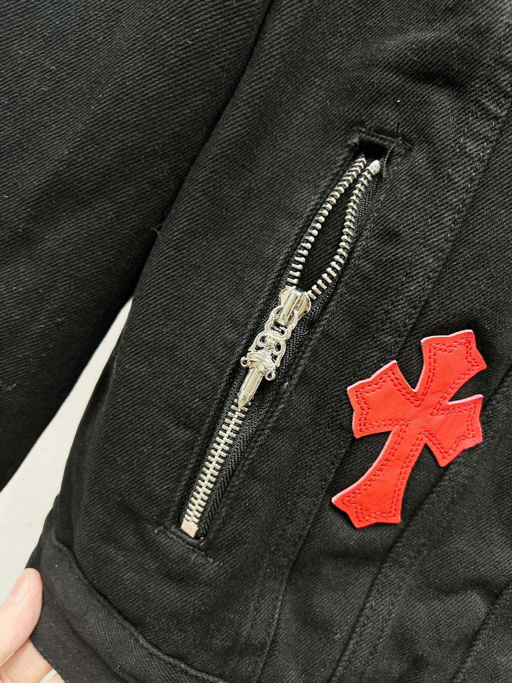 Louis Vuitton denim jacket close-up: silver zipper and red cross patch on dark fabric
