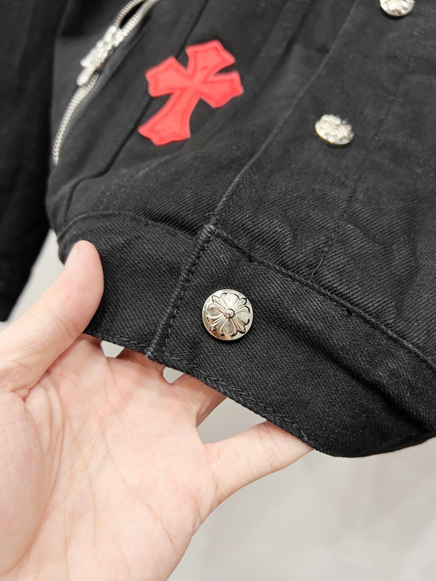 Louis Vuitton denim jacket close-up of hem with silver button and red cross patch