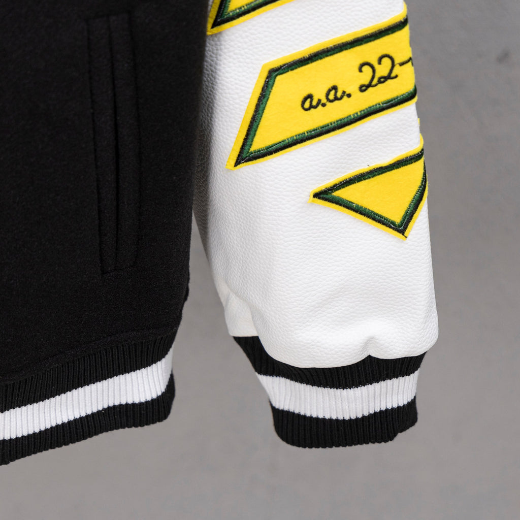 Black-and-white varsity jacket cuffs with ribbed hem and yellow logo trim