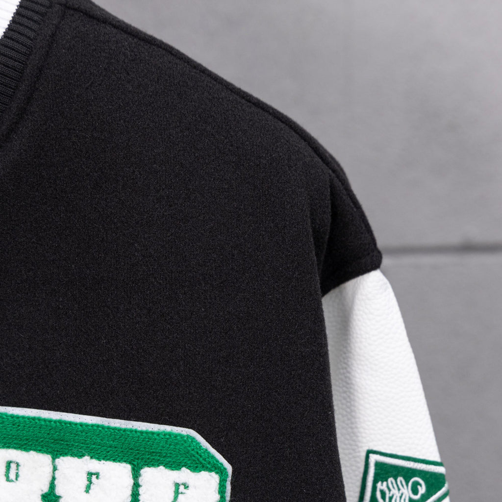 Black varsity jacket sleeve with green patch detail and white striped cuff