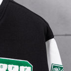 Black varsity jacket sleeve with green patch detail and white striped cuff