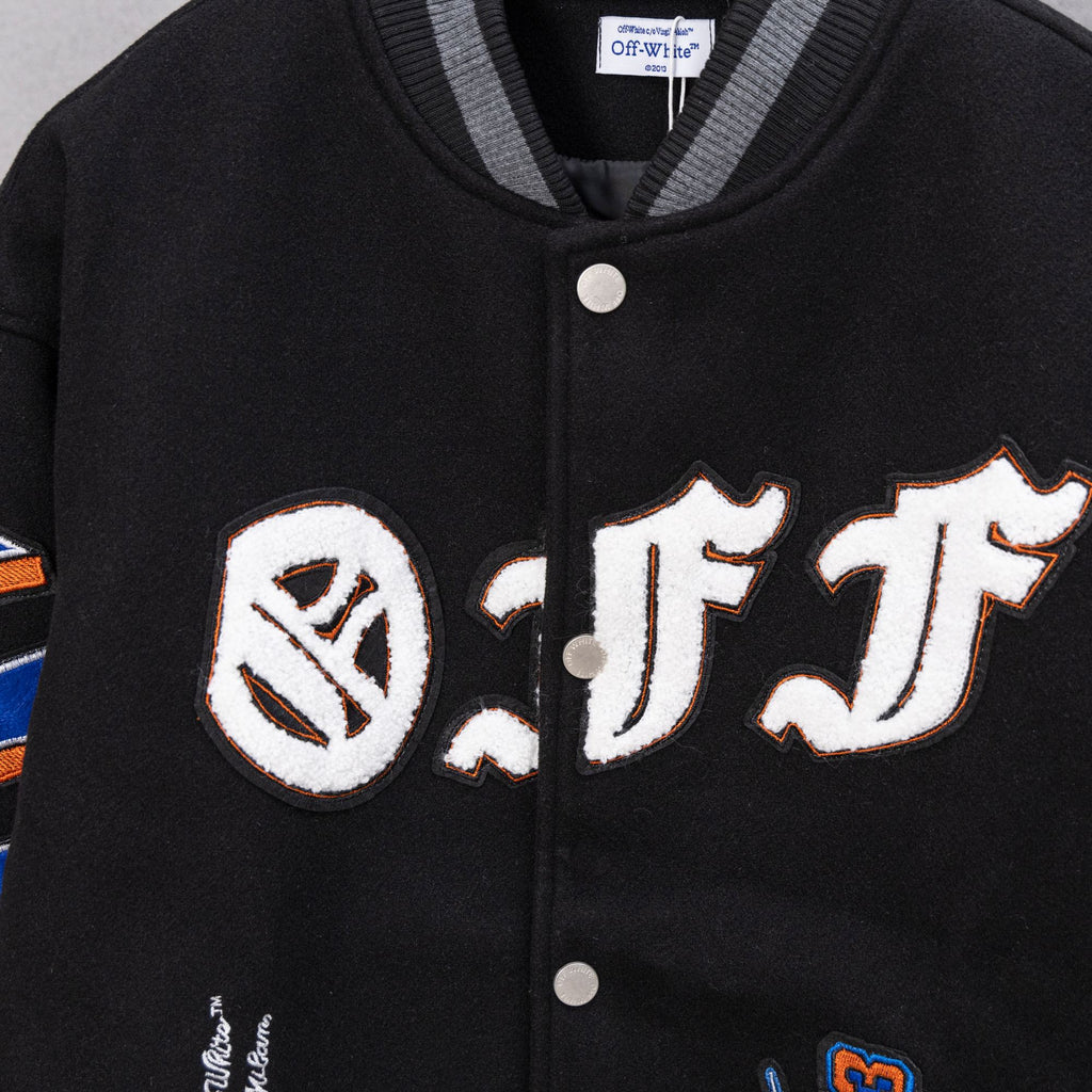 Black varsity jacket front with embroidered monogram patch and snap buttons.