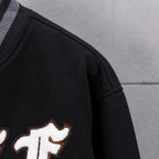 Black varsity jacket sleeve with striped rib cuff and partial embroidered lettering.