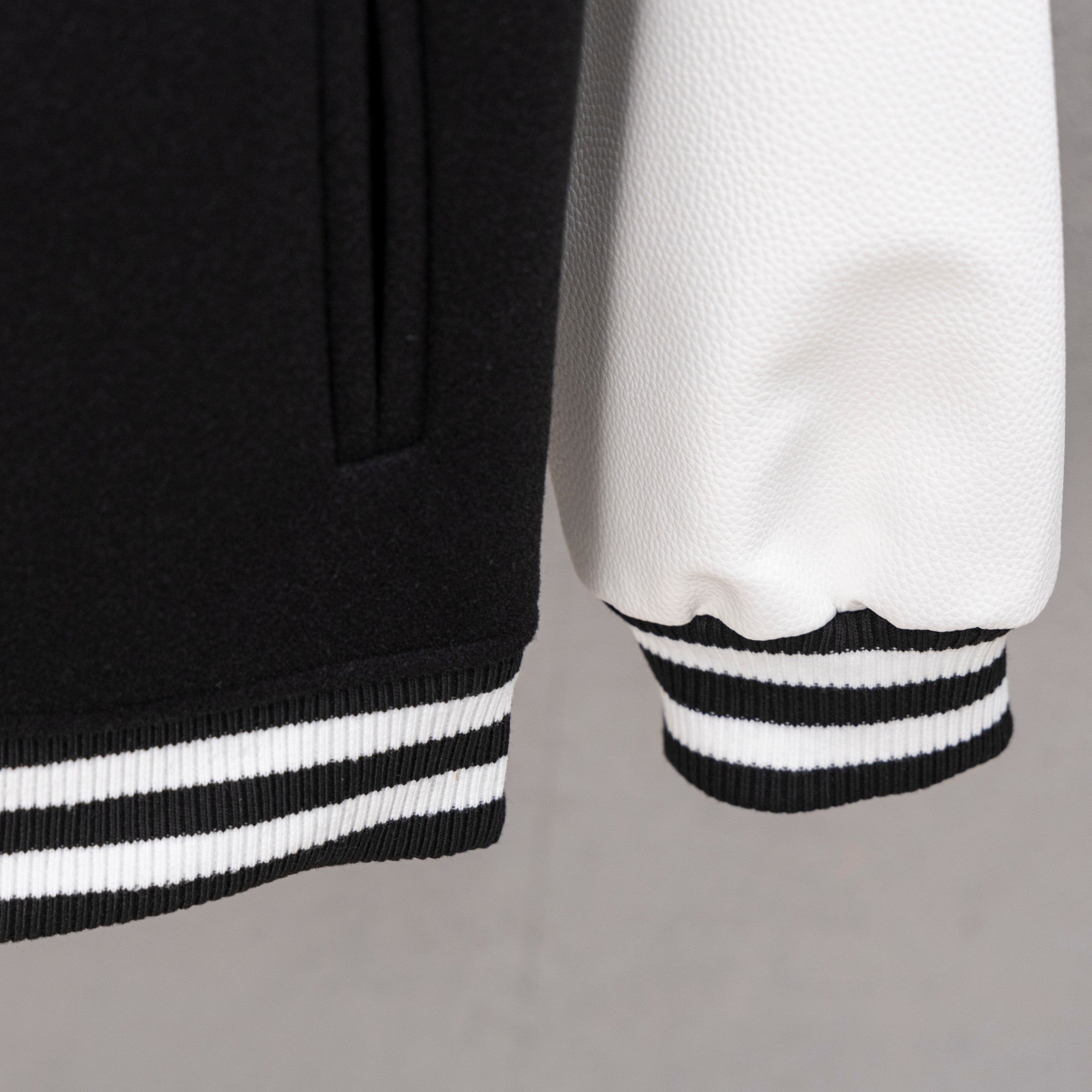 Black jacket hem with striped ribbing and white contrast sleeve