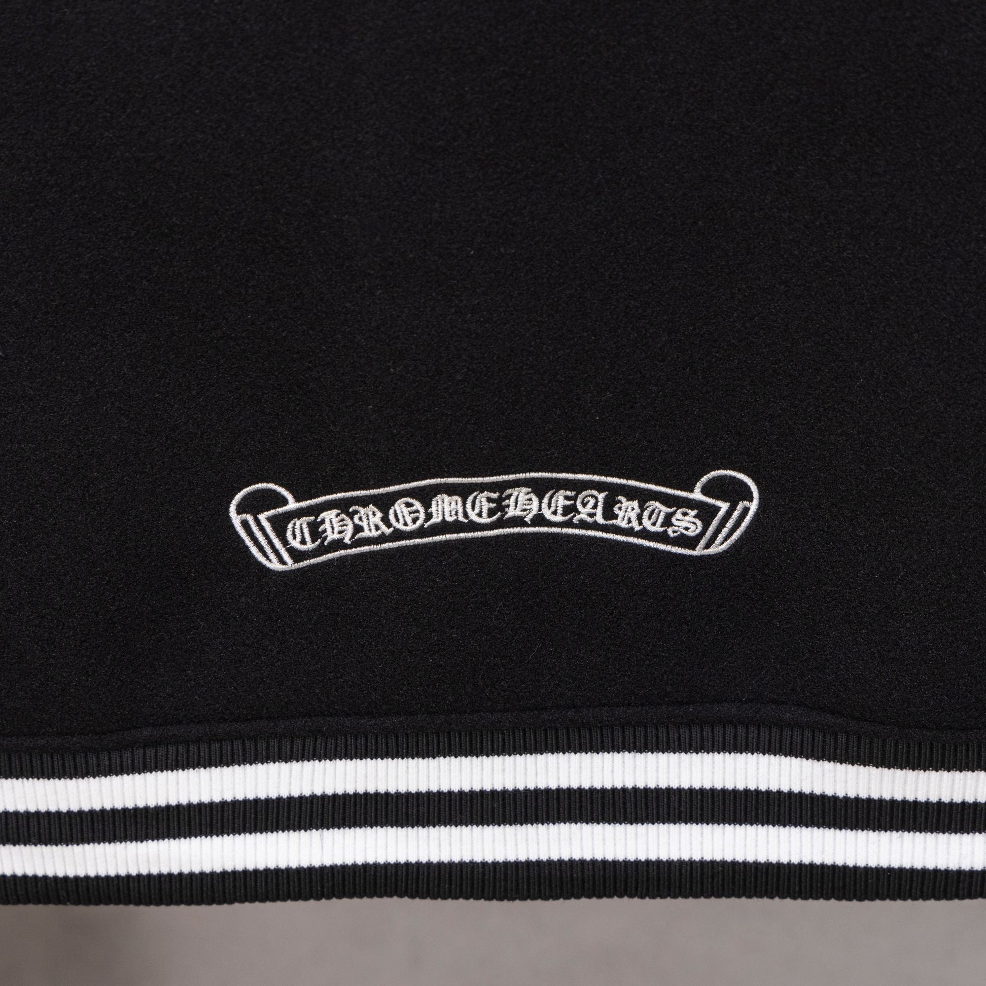 Black jacket chest patch above striped waistband-style trim