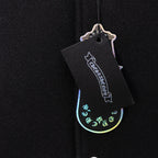 Black clothing tag attached to dark knit jacket fabric