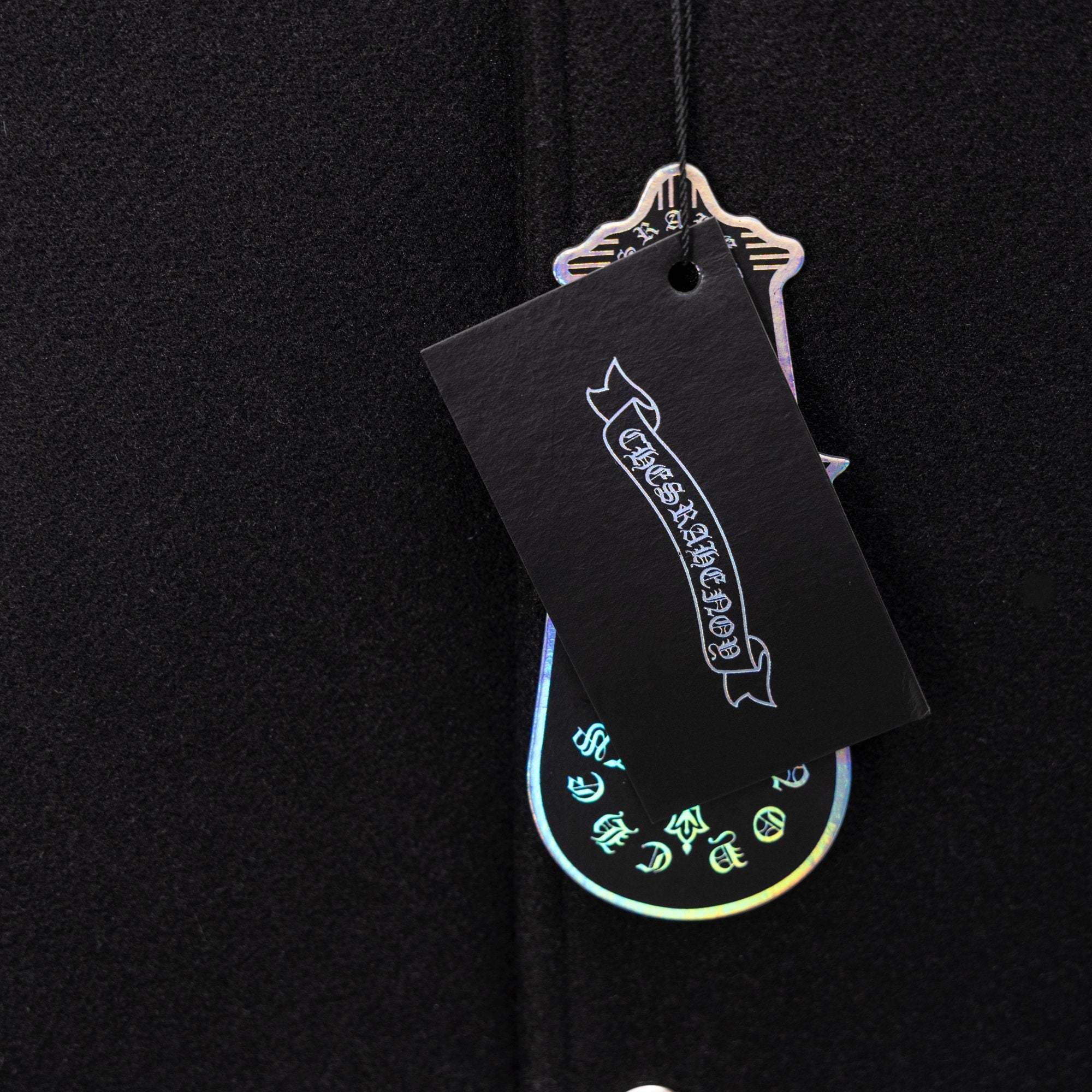 Black clothing tag attached to dark knit jacket fabric