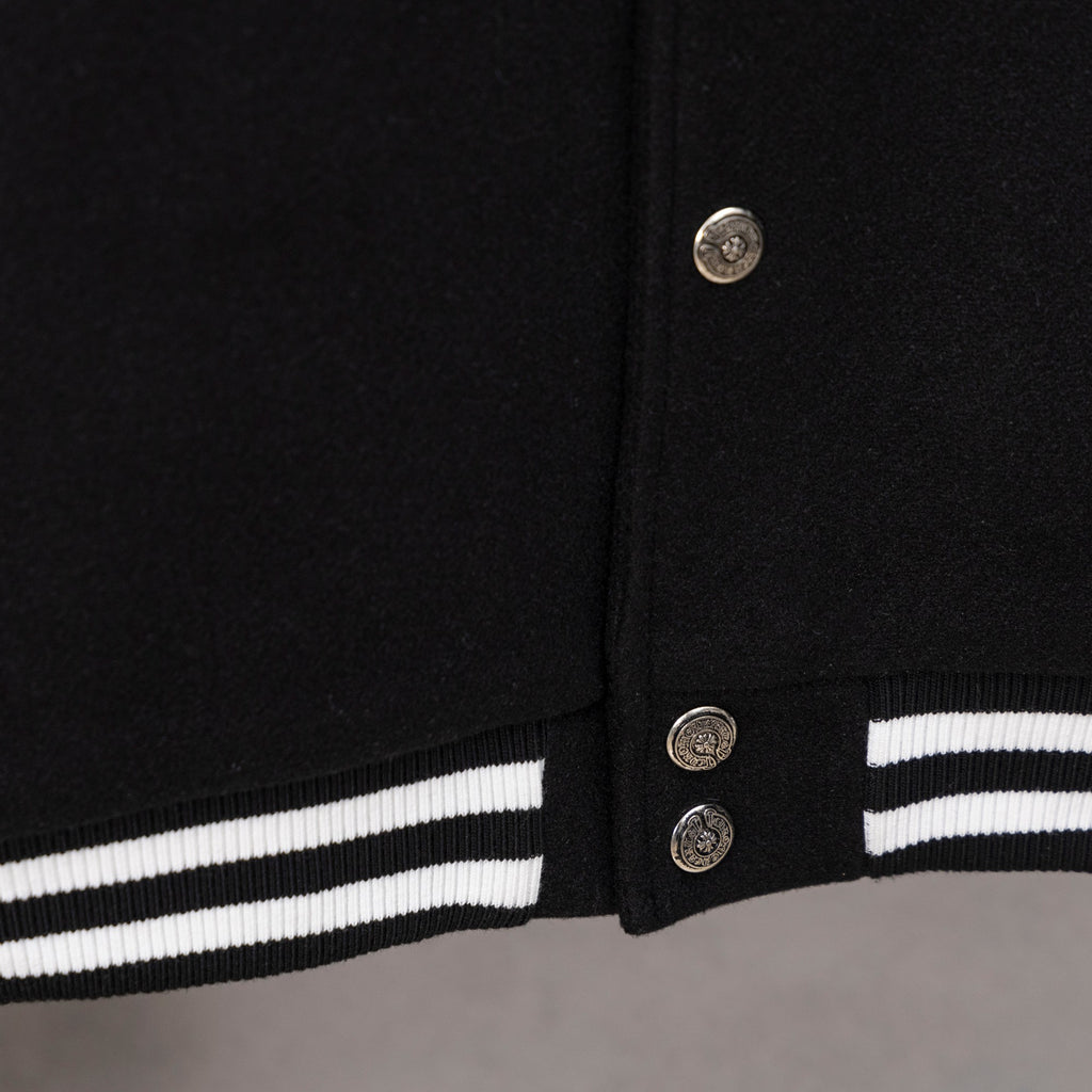 Black snap-front varsity jacket with silver buttons and striped cuff trim