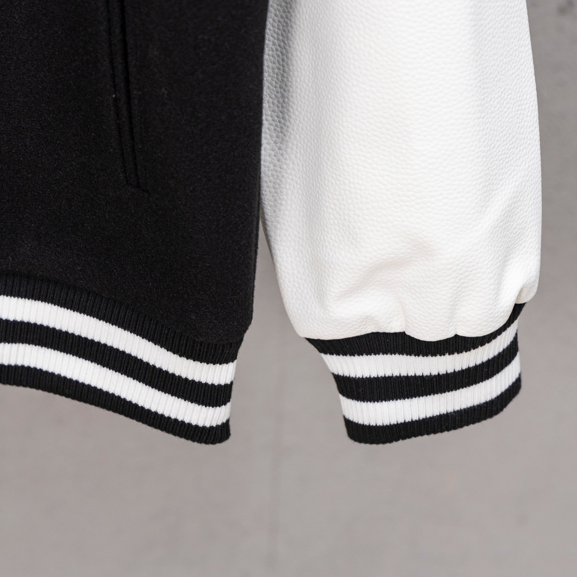 Black and white striped ribbed cuff and hem on varsity jacket sleeve