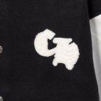 White embroidered cross motif on black varsity jacket front
