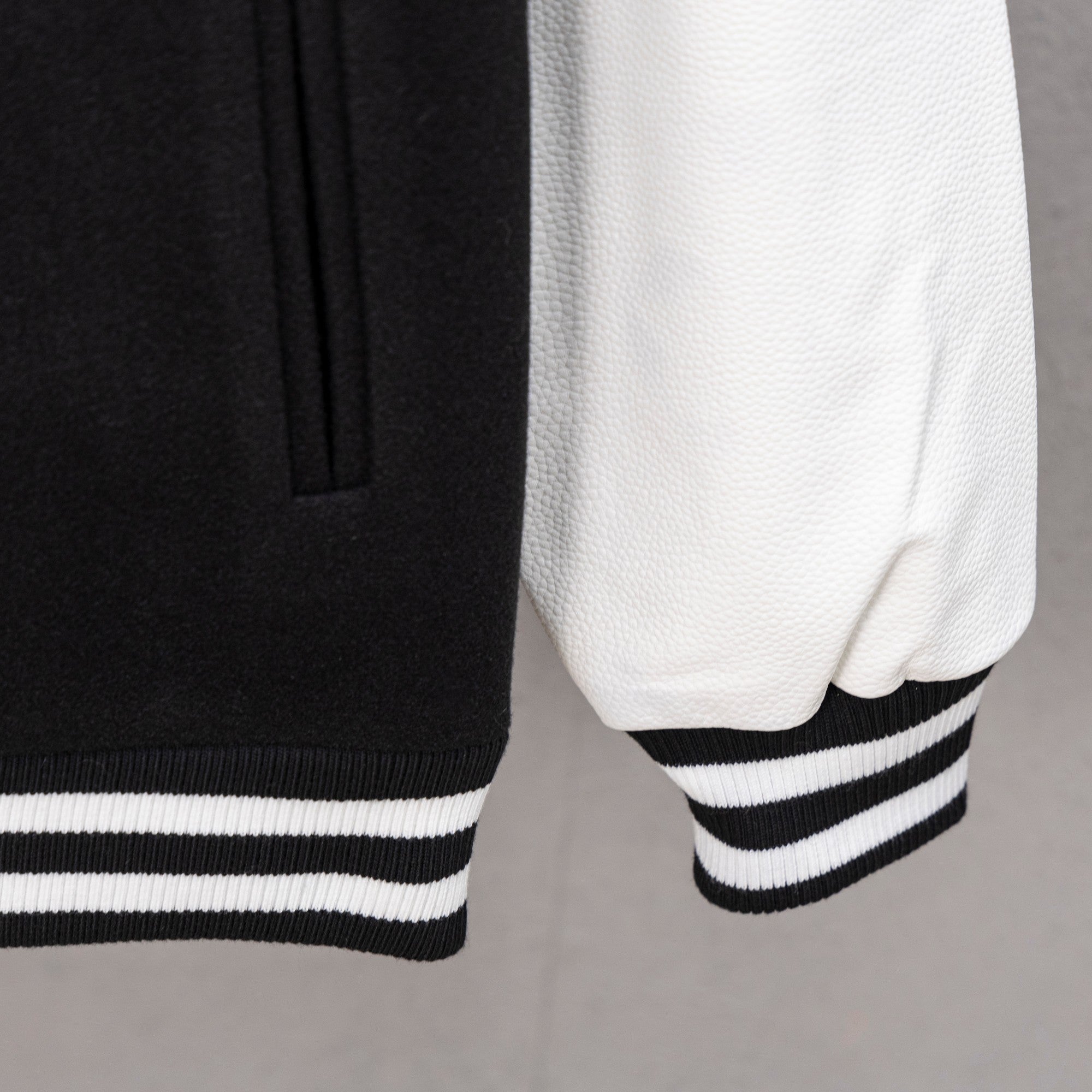 White sleeve with black panel and striped ribbed cuff on varsity jacket