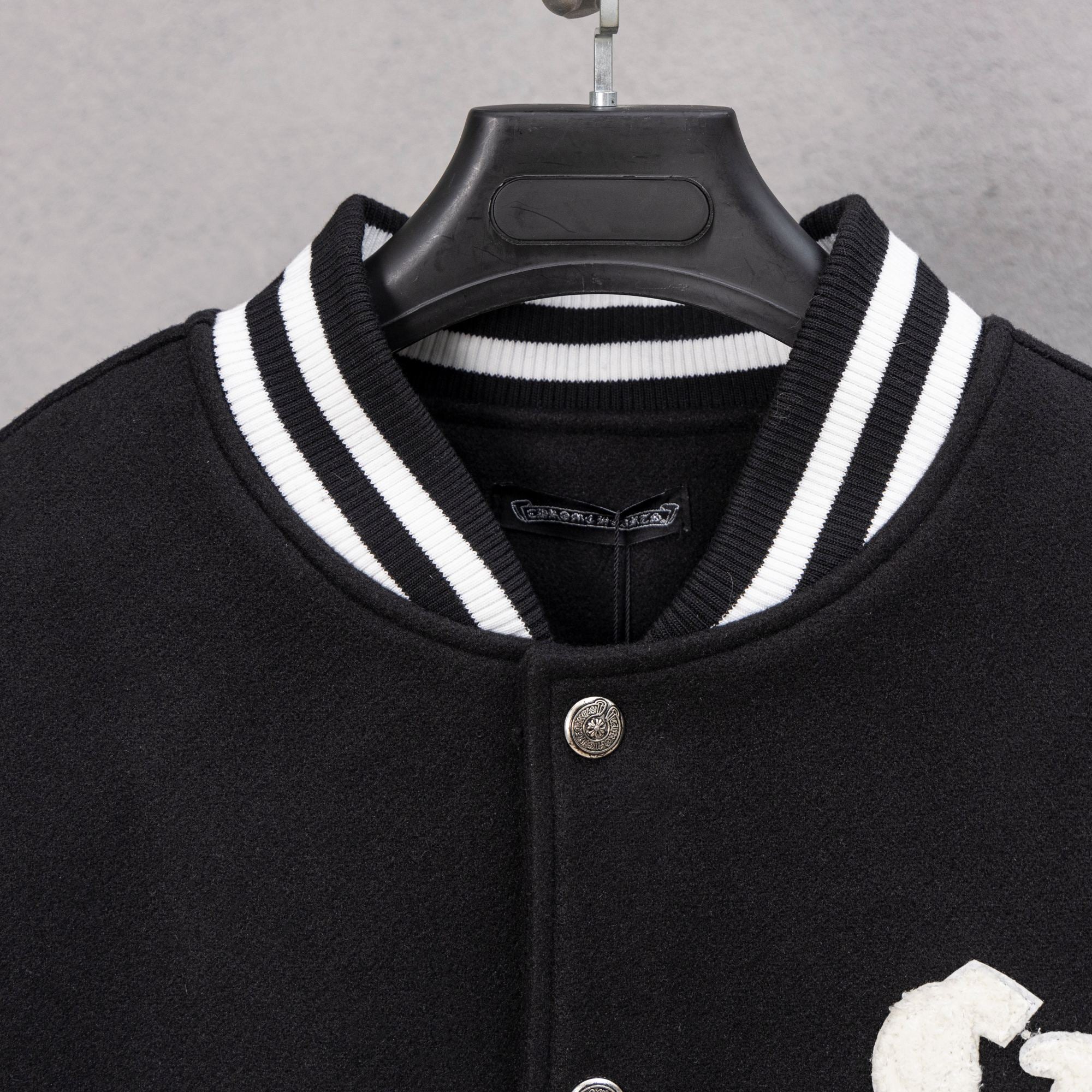 Black varsity jacket with striped ribbed collar and snap button placket