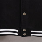Black varsity jacket hem with striped rib trim and snap button closure