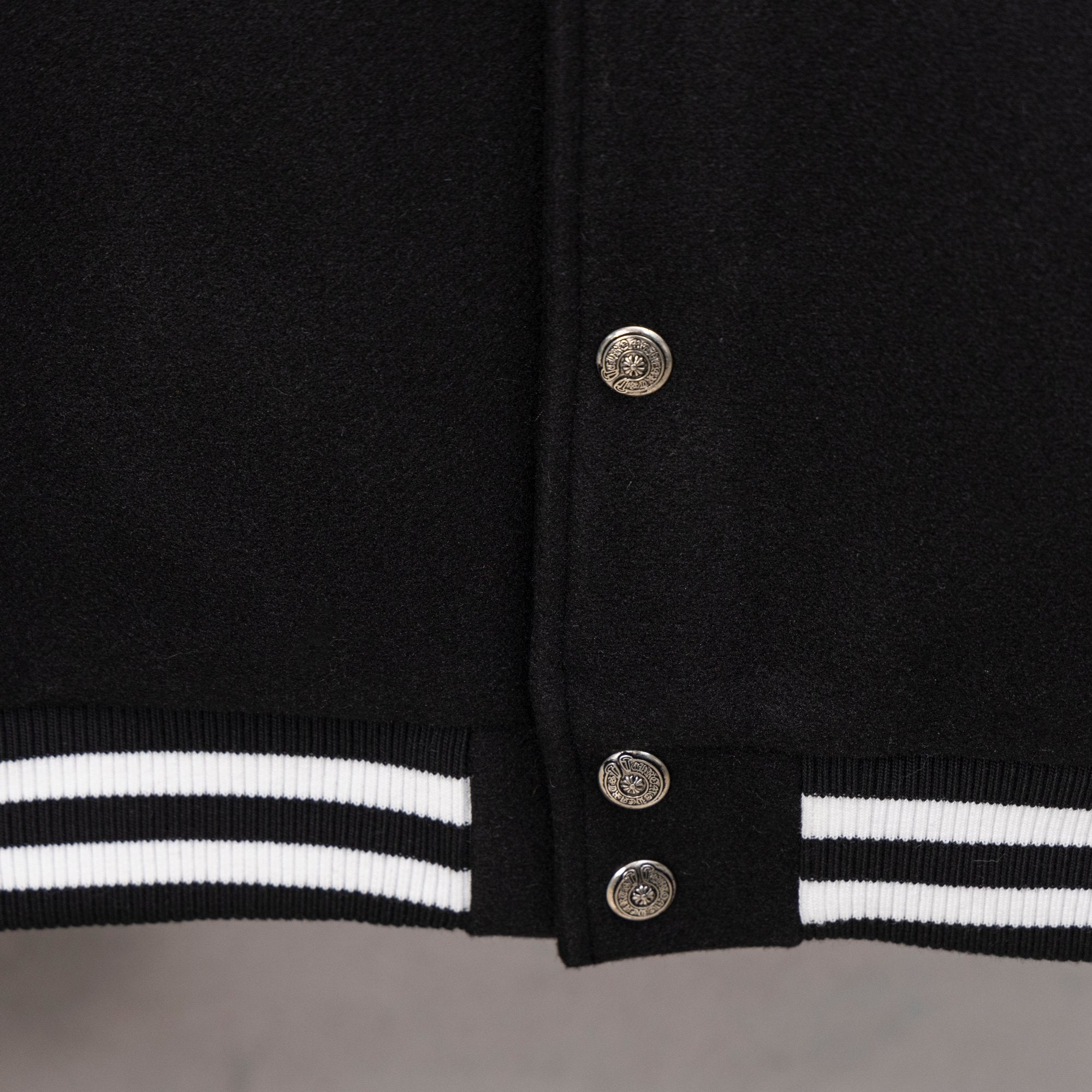Black varsity jacket hem with striped rib trim and snap button closure
