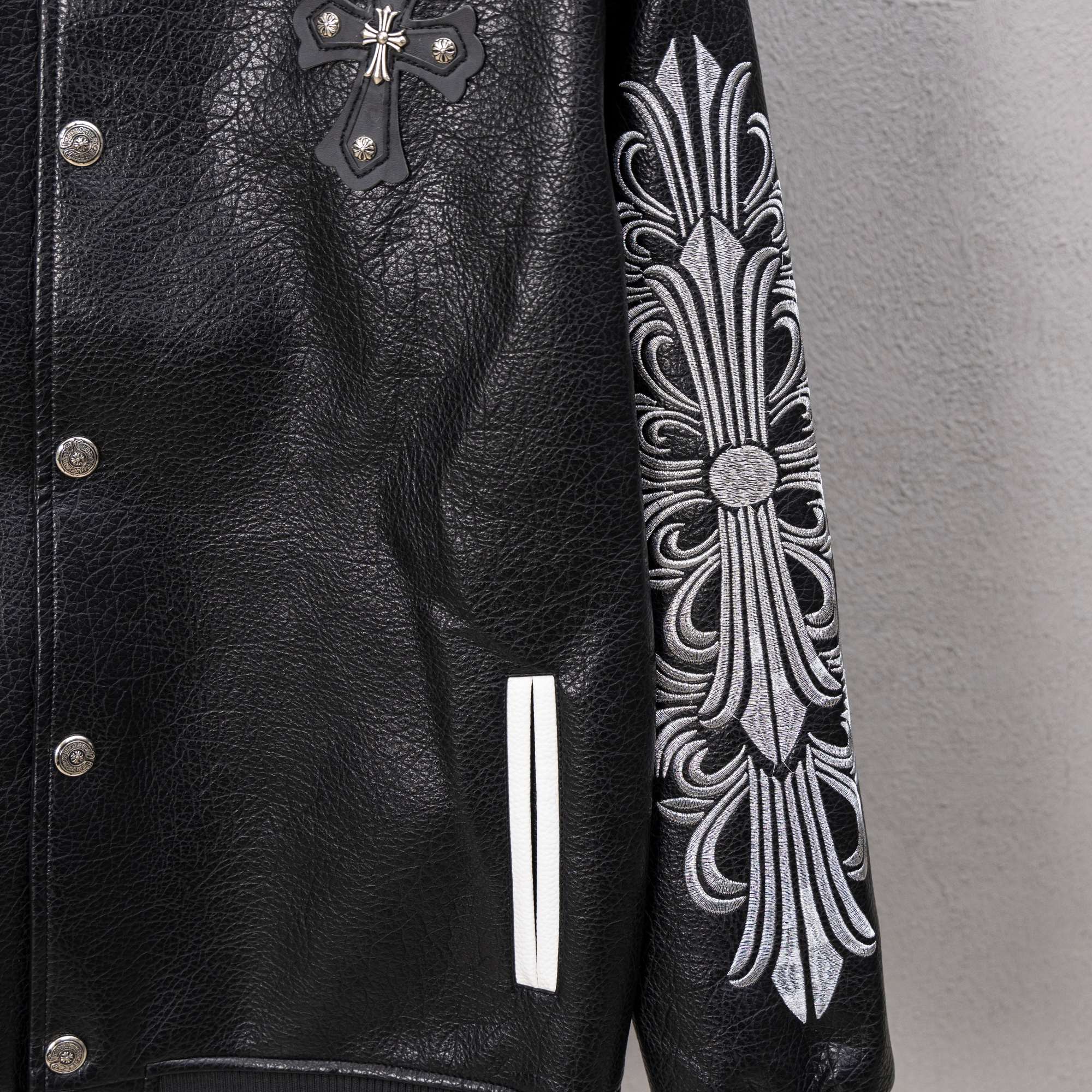 Black leather varsity jacket front with cross applique and ornate sleeve embroidery