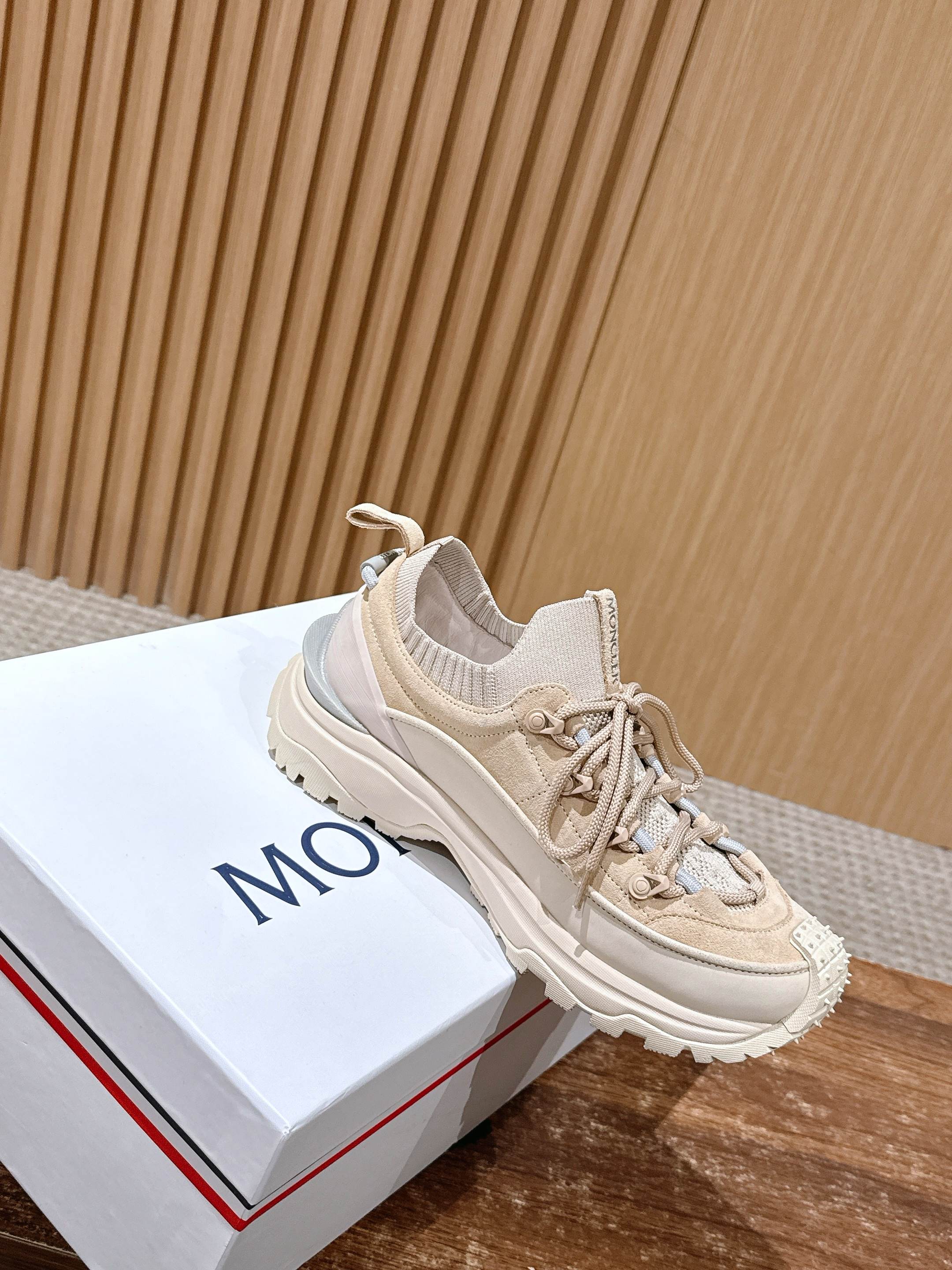 Moncler beige lace-up sneaker with raised sole on a white box.
